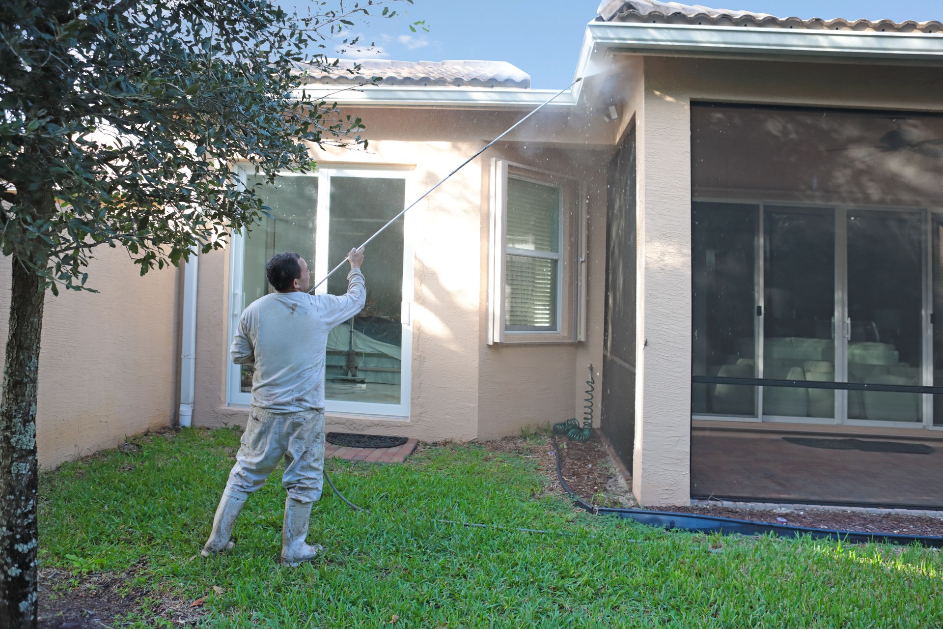 Series:Hispanic worker power washing back of one story home